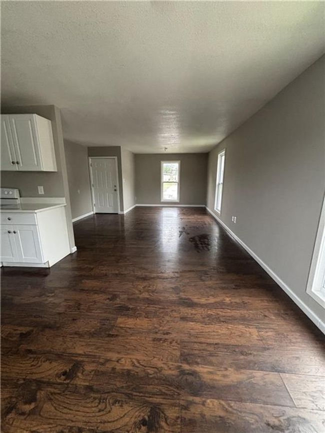 Unfurnished living room featuring a textured ceiling, baseboards, and dark wood-type flooring | Image 12