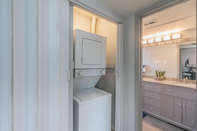 Laundry room with sink, light hardwood / wood-style flooring, and stacked washing maching and dryer | Image 9