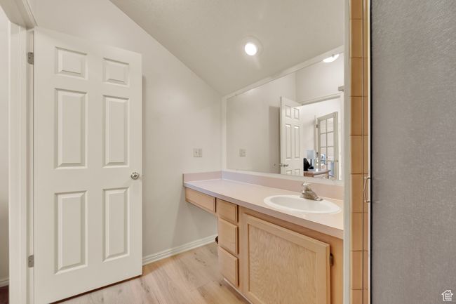 Bathroom featuring vaulted ceiling, vanity, wood finished floors, and baseboards | Image 17