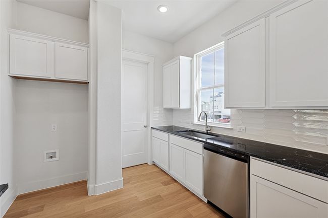 Kitchen with sink, stainless steel dishwasher, tasteful backsplash, and white cabinets | Image 6