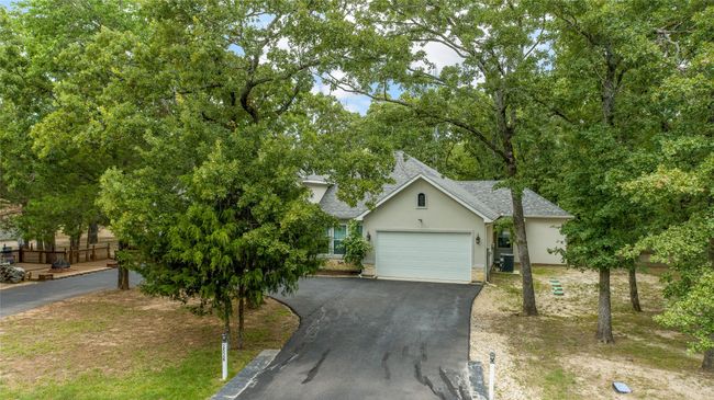 Obstructed view of property with stucco siding, driveway, roof with shingles, and a garage | Image 36