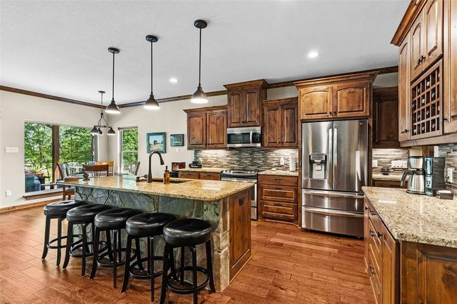 Kitchen featuring stainless steel appliances, tasteful backsplash, hardwood / wood-style flooring, an island with sink, and sink | Image 20