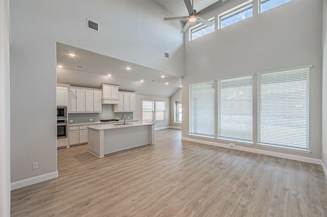 Kitchen with appliances with stainless steel finishes, open floor plan, a towering ceiling, a ceiling fan, and light countertops | Image 12