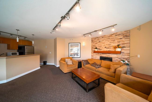 Living room featuring dark colored carpet, a fireplace, baseboards, and track lighting | Image 39