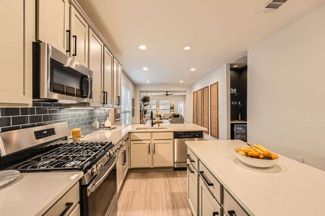 Kitchen featuring light wood-style floors, tasteful backsplash, appliances with stainless steel finishes, light countertops, and a sink | Image 12