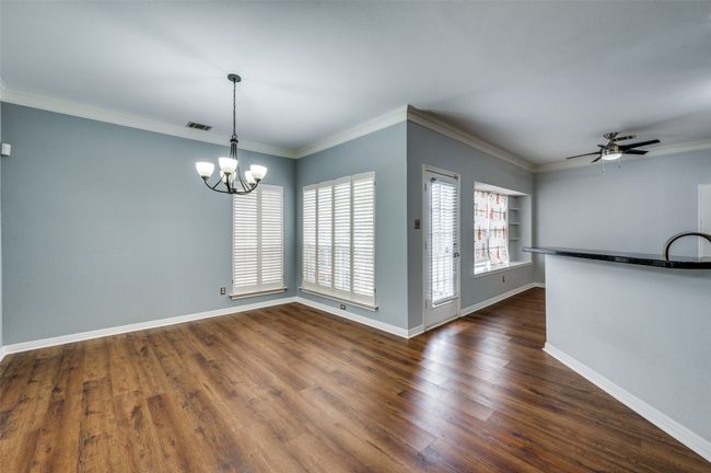 Unfurnished room featuring a chandelier, dark wood finished floors, ceiling fan, built in shelves, and ornamental molding | Image 4