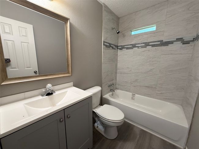 Full bathroom featuring wood finished floors, vanity, toilet, bathing tub / shower combination, and a textured ceiling | Image 12