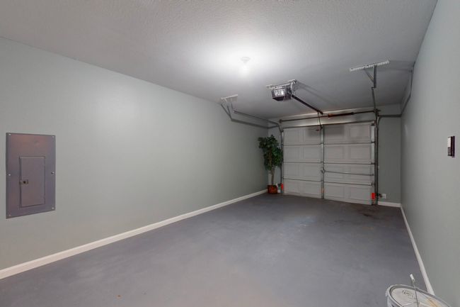 Garage featuring a garage door opener, electric panel, and baseboards | Image 33