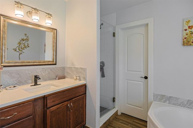 Bathroom with vanity, a shower stall, wood finished floors, backsplash, and a bath | Image 17