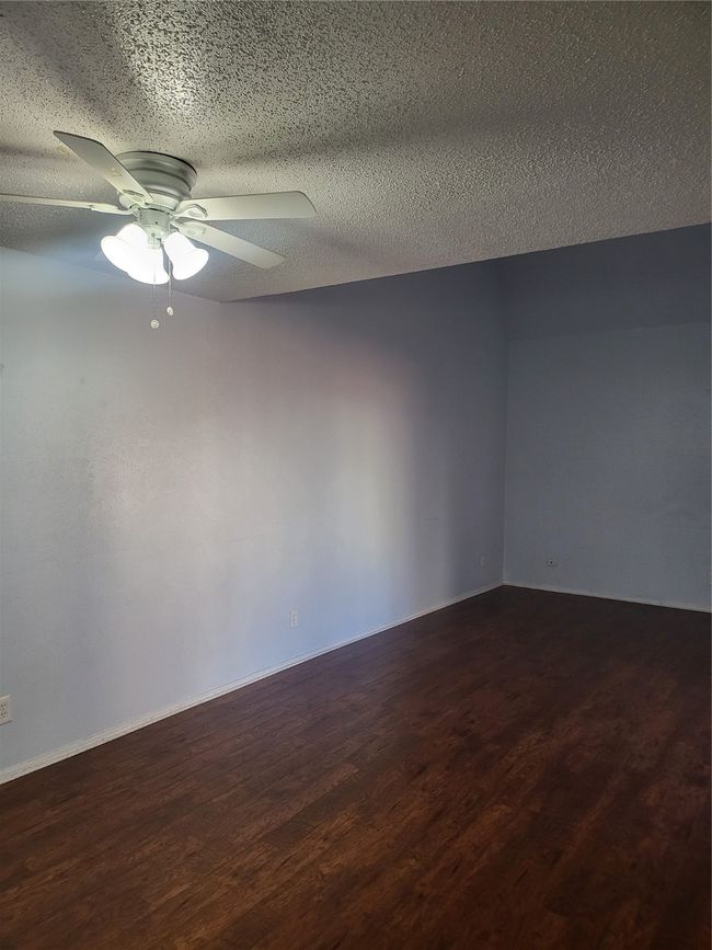 Empty room featuring a ceiling fan, wood finished floors, and a textured ceiling | Image 7