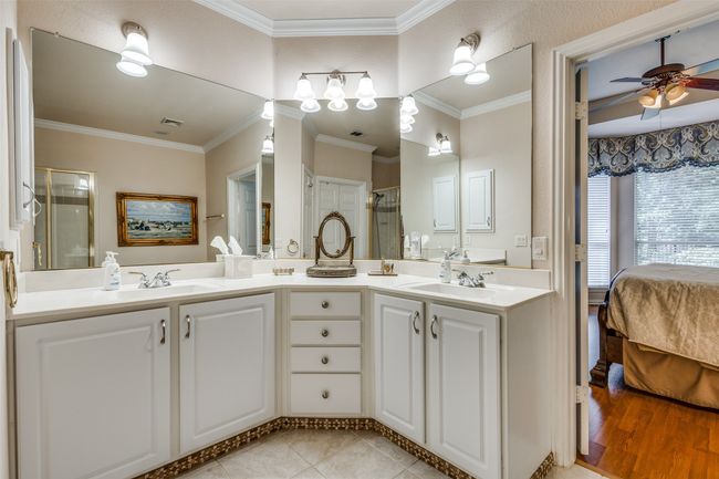 Ensuite bathroom featuring a ceiling fan, double vanity, a shower stall, and ornamental molding | Image 20