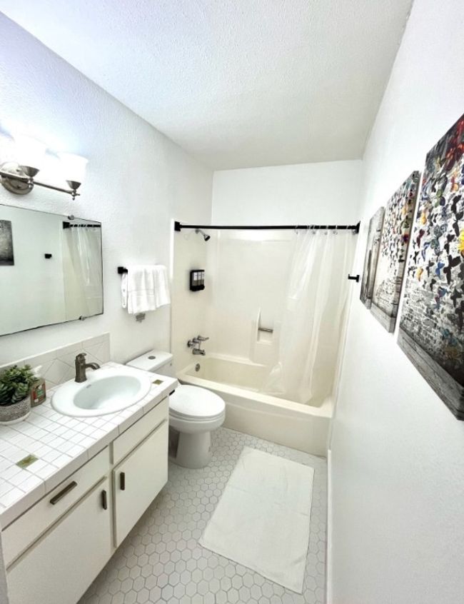 Bathroom with shower / bath combo, vanity, a textured ceiling, and light tile patterned floors | Image 7