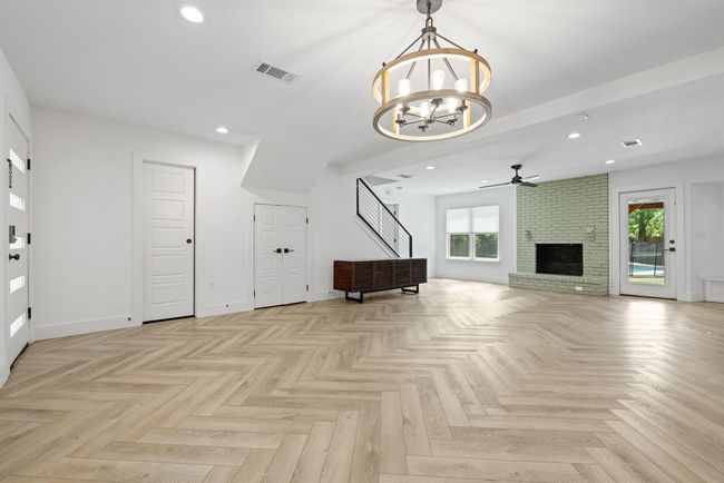 Unfurnished living room with recessed lighting, ceiling fan with notable chandelier, visible vents, and plenty of natural light | Image 11