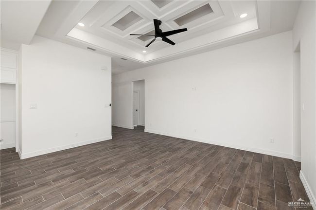 Recessed lighting, a raised ceiling, a ceiling fan, and dark wood-style floors | Image 4
