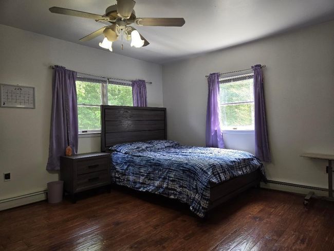 Large, 2nd Floor Bedroom with a baseboard heating unit, light hardwood / wood floors, and a ceiling fan. | Image 25