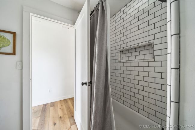 Bathroom with wood finished floors, shower / bathtub combination with curtain, and baseboards | Image 23