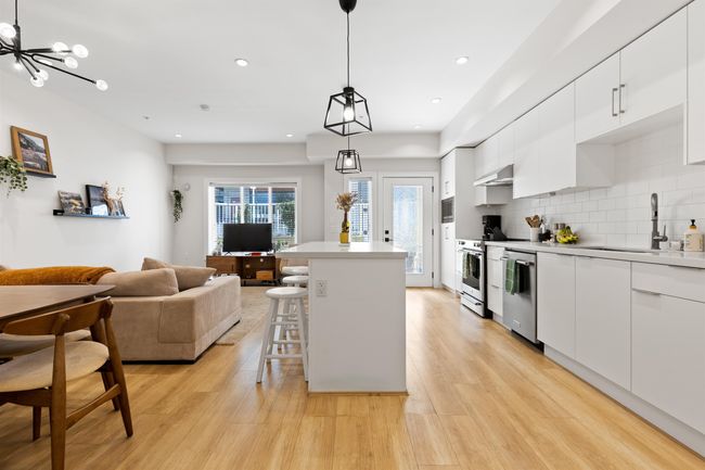 Kitchen with a kitchen bar, light wood-type flooring, white cabinets, under cabinet range hood, and backsplash | Image 18