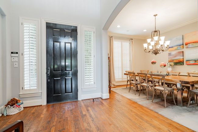 Foyer entrance featuring arched walkways, baseboards, a chandelier, wood finished floors, and ornamental molding | Image 5