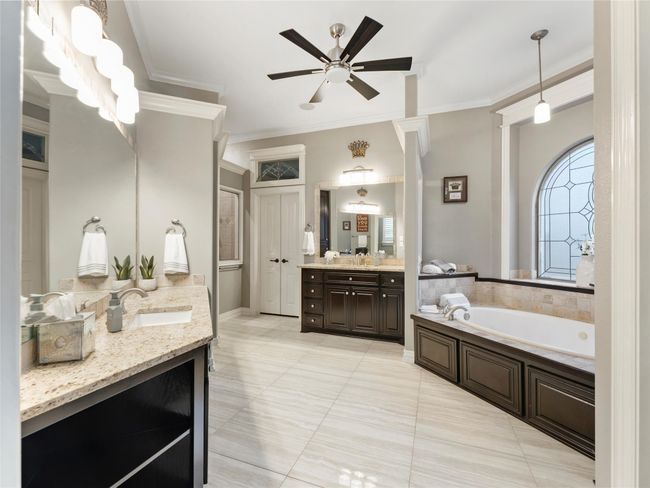 Bathroom featuring a bath, two vanities, a ceiling fan, crown molding, and tile patterned floors | Image 22