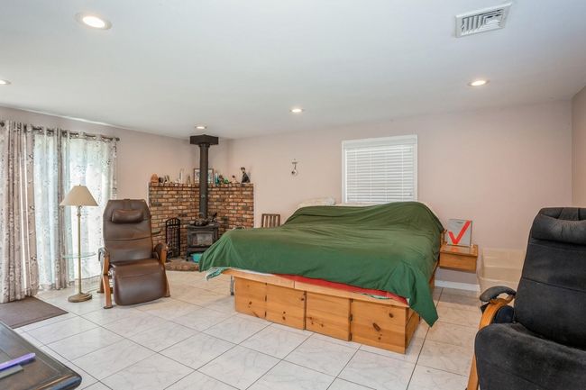 Bedroom featuring visible vents, a wood stove, and recessed lighting | Image 5