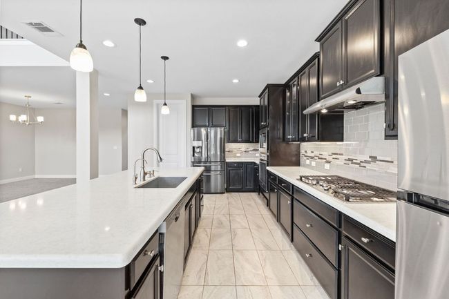 Kitchen featuring stainless steel appliances, under cabinet range hood, marble finish floor, a sink, and visible vents | Image 16