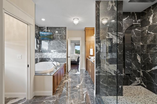 Primary spa-like bathroom is equipped with a jetted soaking tub, dual sinks, and a large walk-in shower. | Image 18