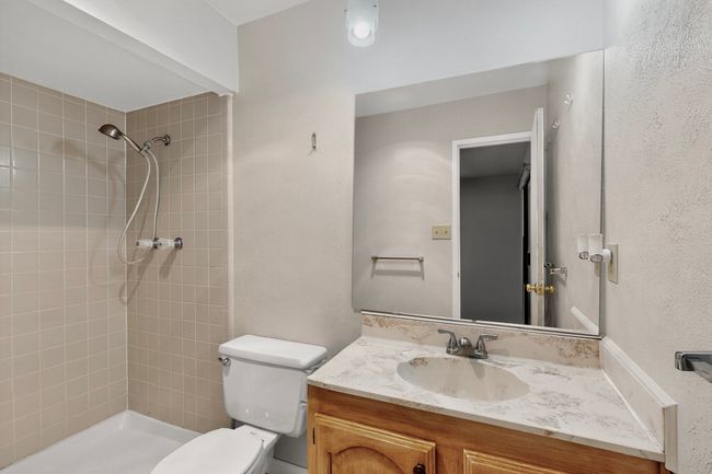 Bathroom featuring a tile shower, vanity, and a textured wall | Image 14