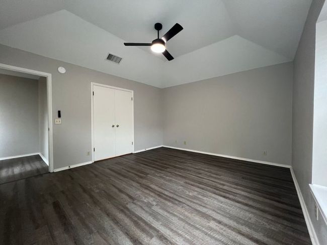 Unfurnished bedroom with dark wood-style floors, ceiling fan, vaulted ceiling, and a closet | Image 26