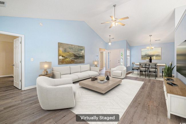 Living room featuring wood finished floors, ceiling fan, a chandelier, and high vaulted ceiling | Image 4