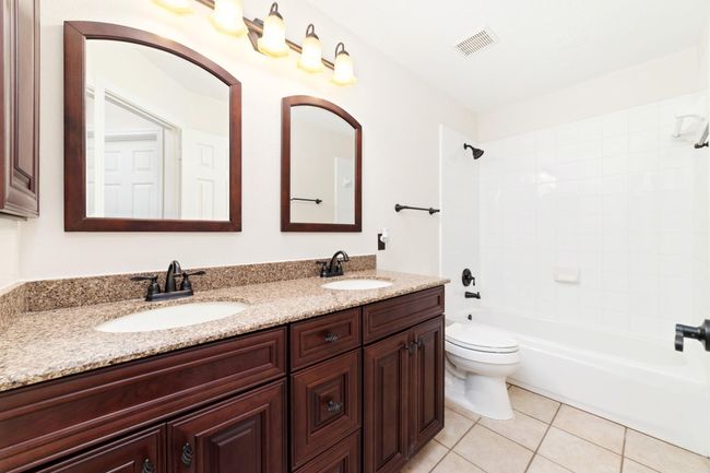 The secondary bathroom features upgraded cabinetry, elegant countertops, and stylish accessories, thoughtfully designed to comfortably serve the three secondary bedrooms. | Image 26