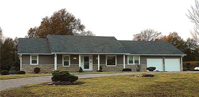 Ranch-style home with covered porch, a garage, and a front lawn | Image 1