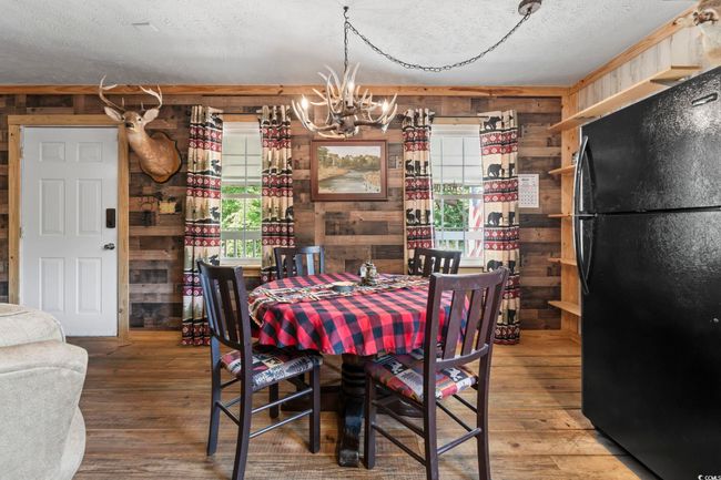 Dining space with wooden walls, a chandelier, hardwood / wood-style floors, and a textured​​‌​​​​‌​​‌‌​‌‌​​​‌‌​​‌‌​‌​​​​​‌ ceiling | Image 12