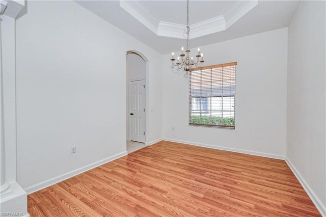 Empty room with an inviting chandelier, crown molding, light hardwood / wood-style flooring, and a raised ceiling | Image 18
