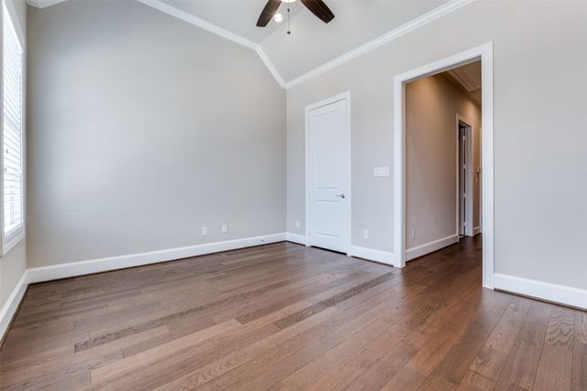 Empty room with crown molding, a ceiling fan, lofted ceiling, and wood finished floors | Image 27