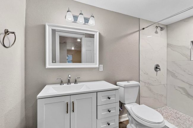 Full bathroom with a marble finish shower, vanity, and a textured wall | Image 12