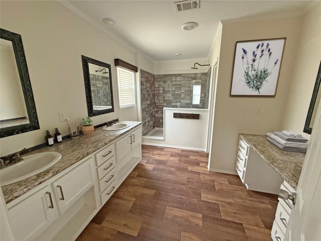 Bathroom featuring crown molding, a walk in shower, double vanity, and wood finished floors | Image 9