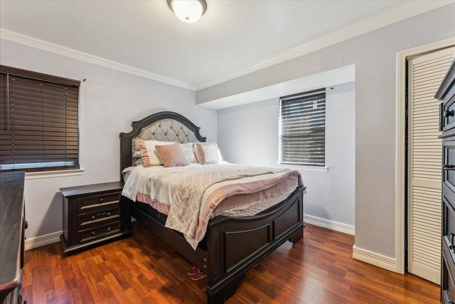Bedroom with baseboards, crown molding, and dark wood finished floors | Image 13