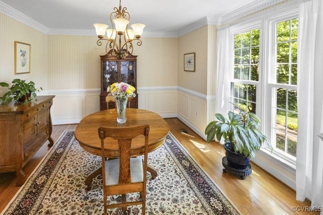 Dining area with wood finished floors, a chandelier, crown molding, a wainscoted wall, and a decorative wall | Image 18