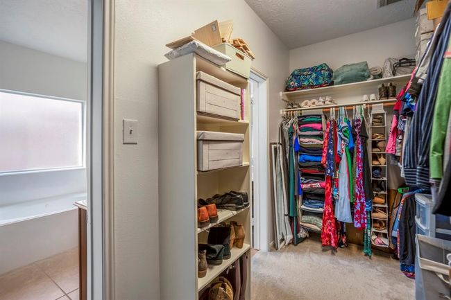 A peek inside the first door reveals the expansive walk-in closet with plenty of hanging space and shelving. The second door leads to the spacious area between the two vanities, offering convenience and privacy in the primary bath layout. | Image 20