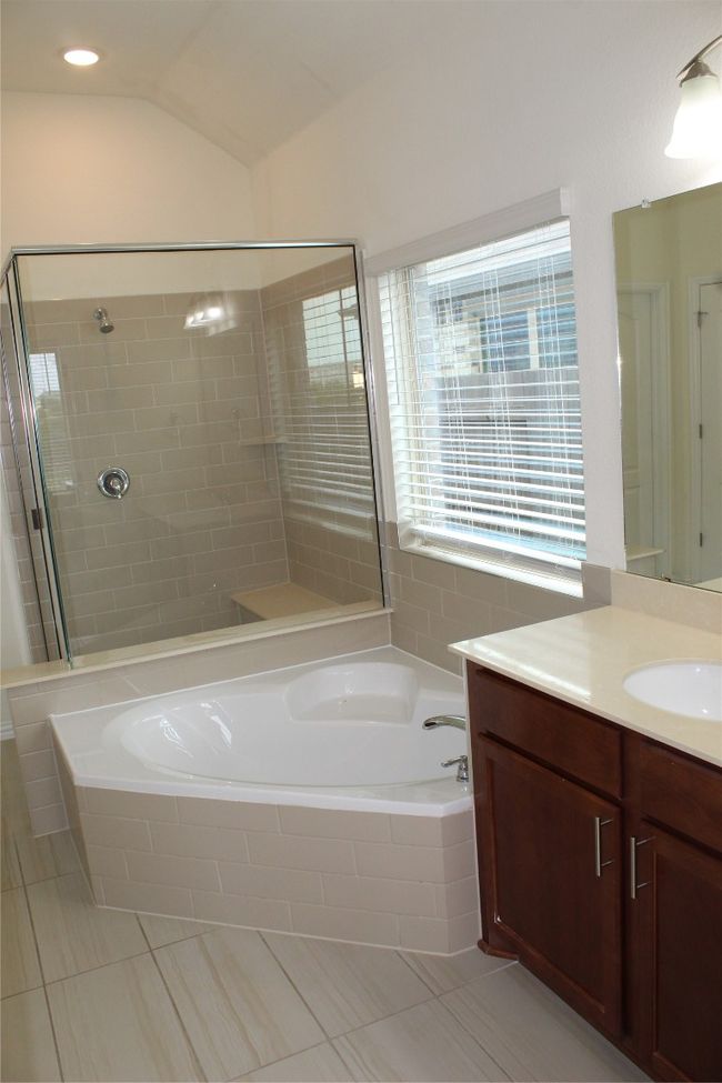 Full bath with tile patterned floors, a garden tub, a stall shower, vanity, and lofted ceiling | Image 22