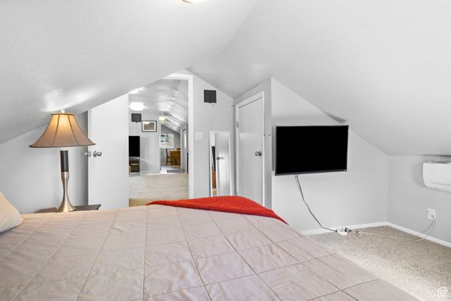 Unfurnished bedroom with a wall mounted air conditioner, baseboards, vaulted ceiling, and carpet | Image 12
