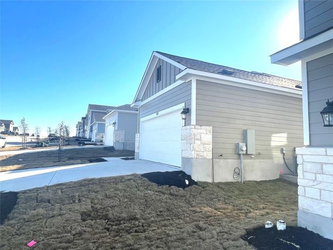 View of property exterior with a garage, board and batten siding, concrete driveway, and stone siding | Image 4
