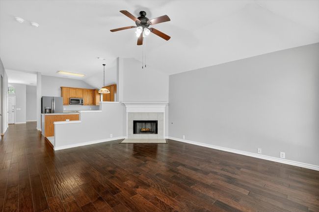 Living room featuring ceiling fan, lofted ceiling, dark wood finished floors, and a tile fireplace | Image 10