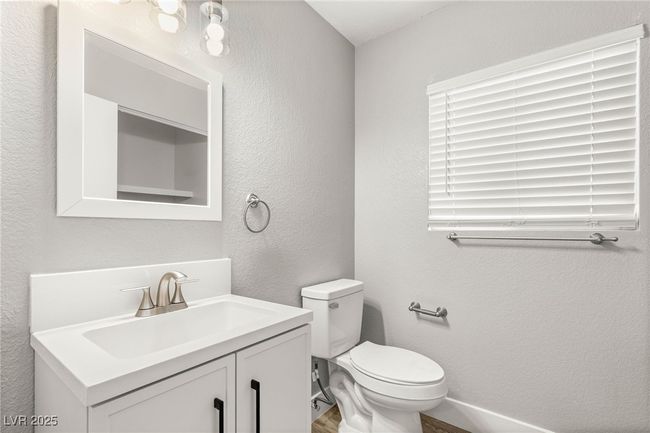 Bathroom with a textured wall, wood finished floors, toilet, vanity, and baseboards | Image 18