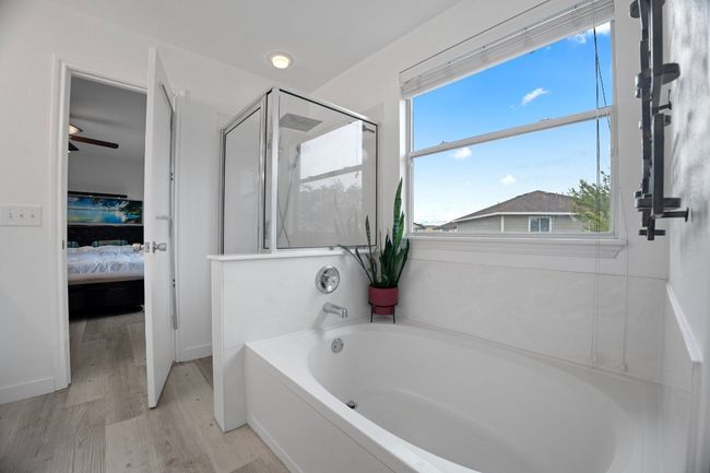 Bathroom with connected bathroom, a garden tub, a shower stall, and wood finished floors | Image 22