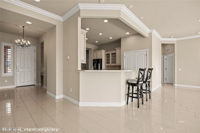 Kitchen with a notable chandelier, baseboards, black fridge, crown molding, and light tile patterned flooring | Image 24