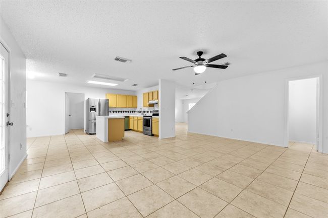 Kitchen featuring stainless steel appliances, open floor plan, under cabinet range hood, light countertops, and a textured ceiling | Image 9
