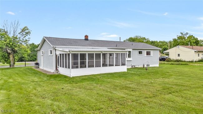 Rear view of property with a chimney, a sunroom, a lawn, and roof with shingles | Image 26