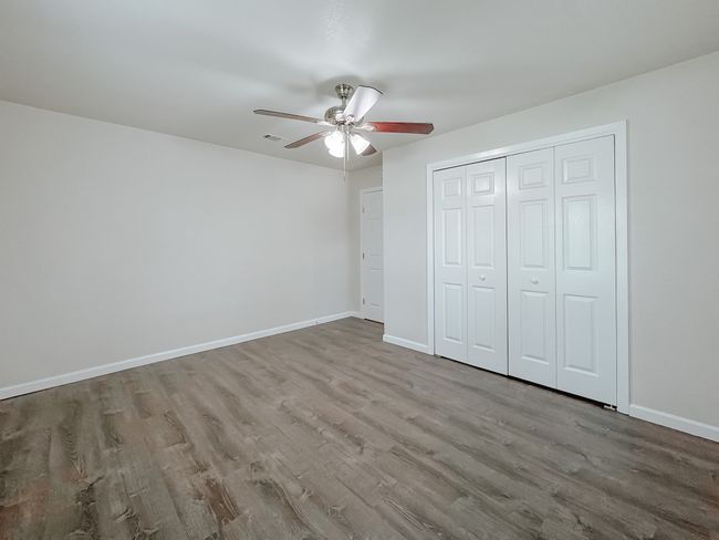 Unfurnished bedroom featuring wood finished floors, a closet, and a ceiling fan | Image 25