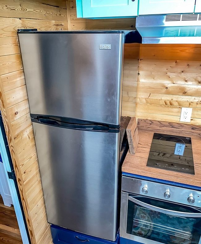 Kitchen view of stainless steel appliances, wood walls, and blue cabinetry | Image 25